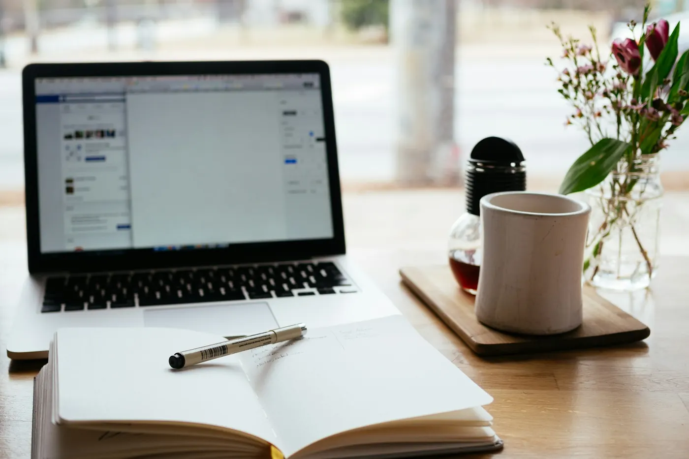 Laptop, open notebook and coffee on a writer's desk