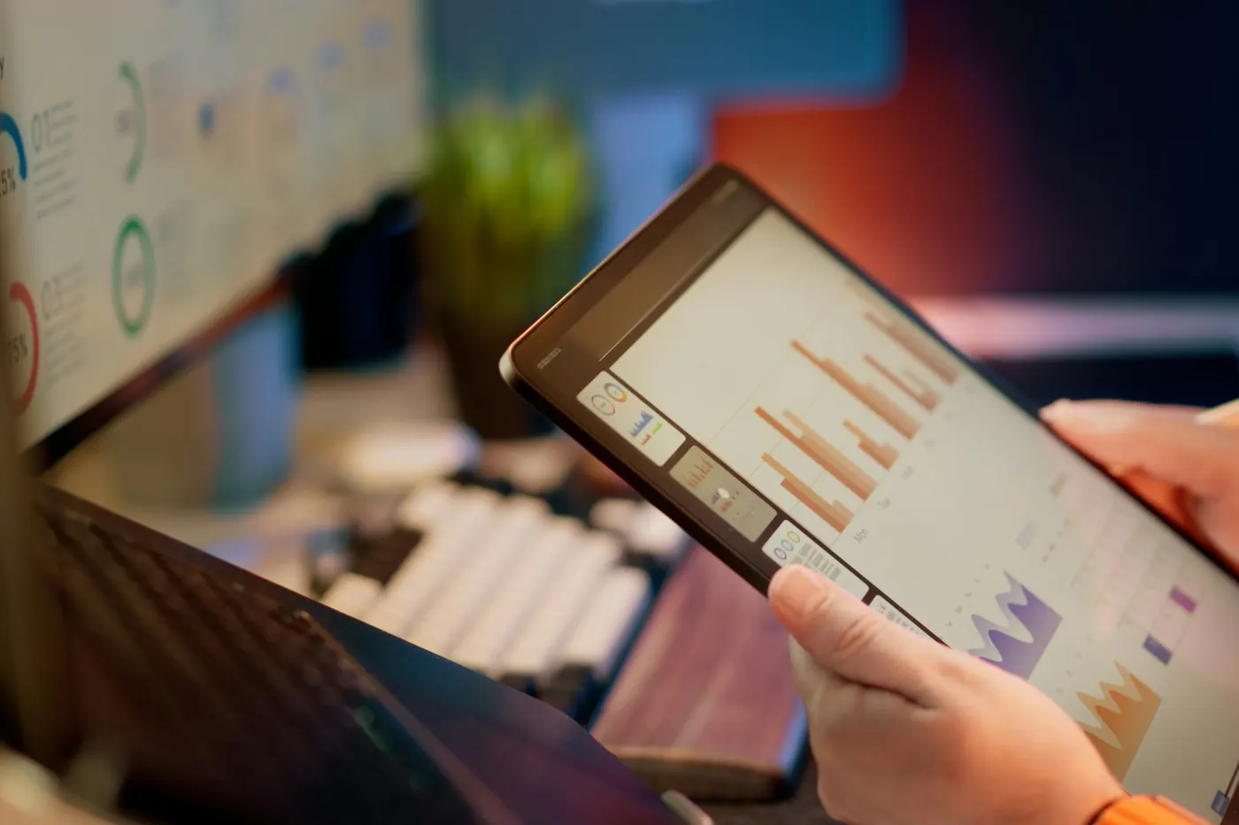Hands holding a tablet displaying charts and figures