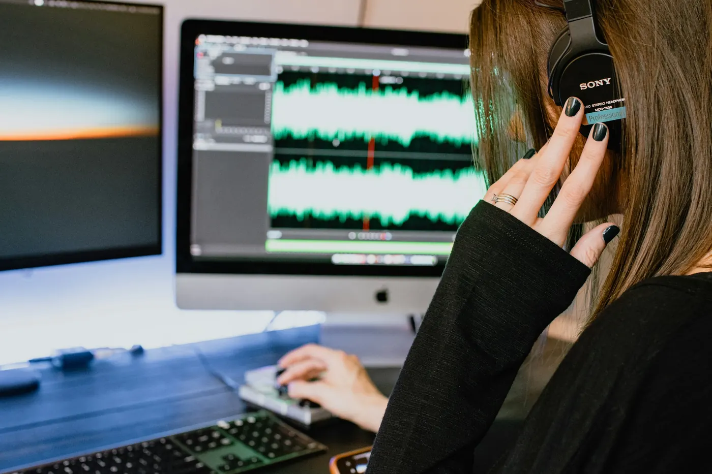 Transcriber wearing headphones working with an audio waveform on screen